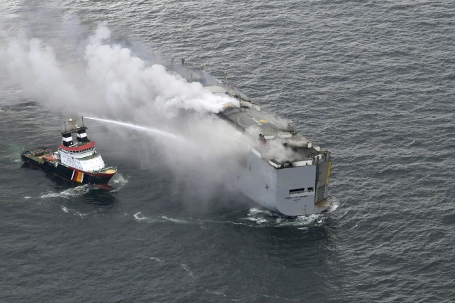 A freighter carrying nearly 3,000 cars catches fire in the North Sea and a crew member is killed