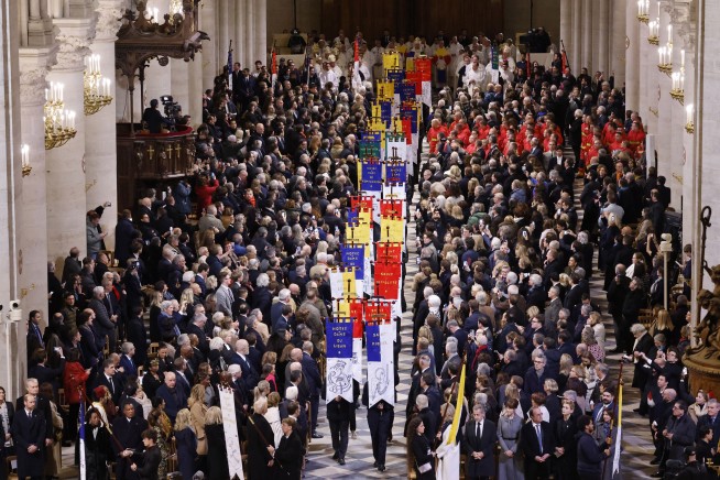 An archbishop's knock formally restores Notre Dame to life as winds howl and heads of state look on
