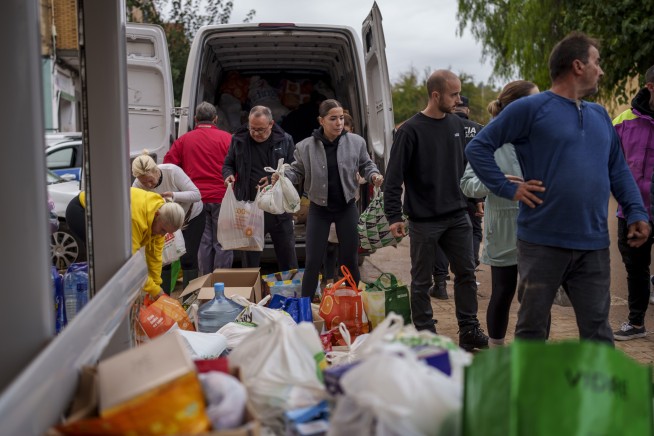 Mud-caked volunteers clean flood debris in a Spanish town as authorities struggle to respond