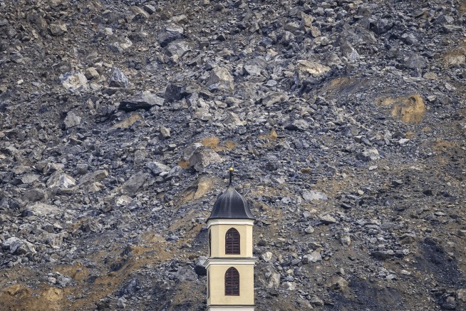 Mass of rock slides down Swiss mountainside above evacuated village, narrowly missing settlement