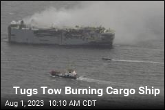 Tugs Tow Burning Cargo Ship